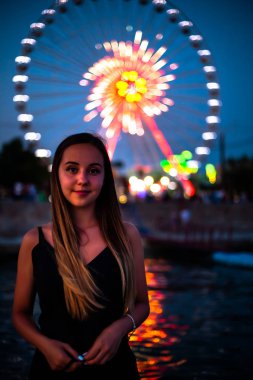 Geceleri dönme dolabın arka planında mutlu bir kız. Gece ışıkları dönme dolap.