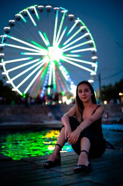 Geceleri dönme dolabın arka planında mutlu bir kız. Gece ışıkları dönme dolap.