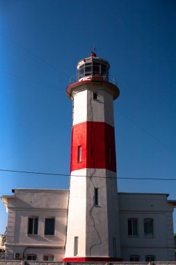 Deniz fenerinin fotoğrafı. Parlak mavi gökyüzü ve kırmızı beyaz deniz feneri.