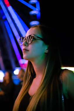 Bir eğlence parkı gece neon ışıklar güzel kız.