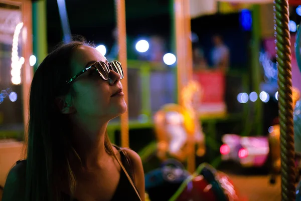 遊園地で夜のネオンライトで美しい女の子 — ストック写真