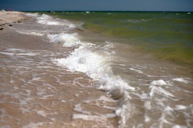 Kumlu bir plajın kıyısında sıçramaları ile deniz dalgaları.