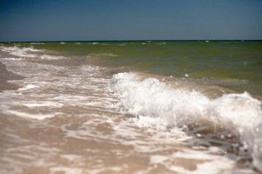 Kumlu bir plajın kıyısında sıçramaları ile deniz dalgaları.