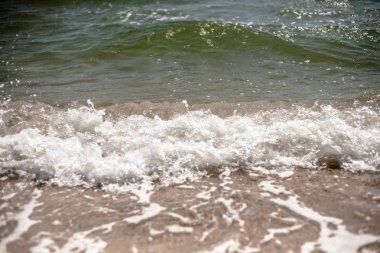 Kumlu bir plajın kıyısında sıçramaları ile deniz dalgaları.