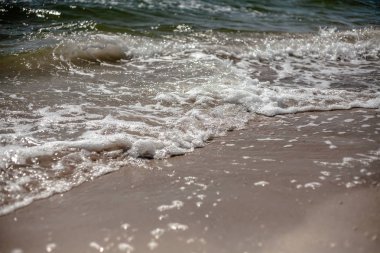 Kumlu bir plajın kıyısında sıçramaları ile deniz dalgaları.