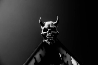 Evin çatısında boynuzları olan şeytan kafası. Arka plan.