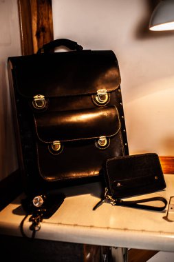 Deri evrak çantası çantası, cüzdan ve el yapımı saat standı masada.