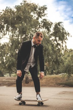 Klasik siyah takım elbiseli bir adam. Kaykay, ücretsiz yaşam konsepti.