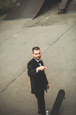 Klasik siyah takım elbiseli bir adam. Kaykay, ücretsiz yaşam konsepti.