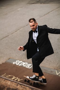 Klasik siyah takım elbiseli bir adam. Kaykay, ücretsiz yaşam konsepti.