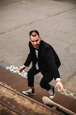 Klasik siyah takım elbiseli bir adam. Kaykay, ücretsiz yaşam konsepti.