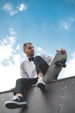 Klasik siyah takım elbiseli bir adam. Kaykay, ücretsiz yaşam konsepti.