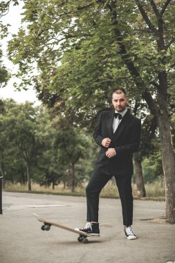 Klasik siyah takım elbiseli bir adam. Kaykay, ücretsiz yaşam konsepti.