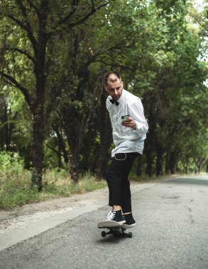 Klasik siyah takım elbiseli bir adam. Kaykay, ücretsiz yaşam konsepti.