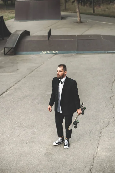 A guy in a classic black suit. Skateboarding, free life concept.