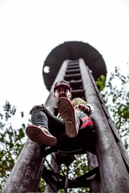 Şık giyimli adam, terk edilmiş bir yerde paslı bir arka plan üzerinde.