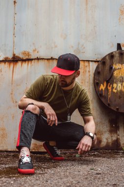 Şık giyimli adam, terk edilmiş bir yerde paslı bir arka plan üzerinde.