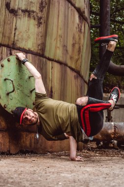 Şık giyimli adam, terk edilmiş bir yerde paslı bir arka plan üzerinde. Aradaki öğeleri gerçekleştirir.