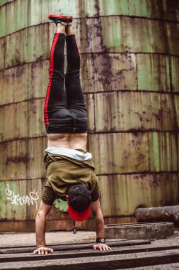 Şık giyimli adam, terk edilmiş bir yerde paslı bir arka plan üzerinde. Aradaki öğeleri gerçekleştirir.