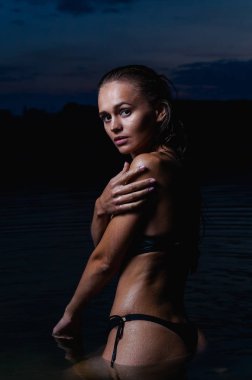 Suda güzel bir model. Gece için siyah bikini mayo, yüzme ve poz.