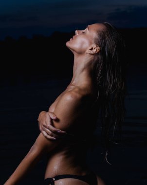 Suda güzel bir model. Gece için siyah bikini mayo, yüzme ve poz.