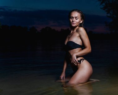 Suda güzel bir model. Gece için siyah bikini mayo, yüzme ve poz.