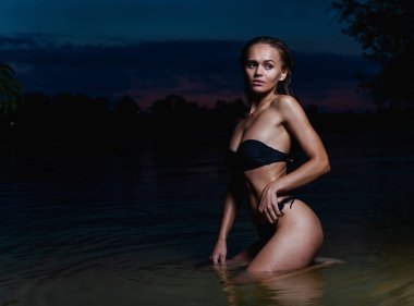 Suda güzel bir model. Gece için siyah bikini mayo, yüzme ve poz.