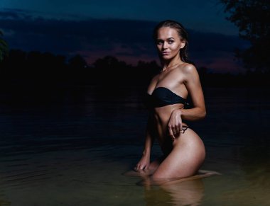 Suda güzel bir model. Gece için siyah bikini mayo, yüzme ve poz.