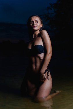Suda güzel bir model. Gece için siyah bikini mayo, yüzme ve poz.