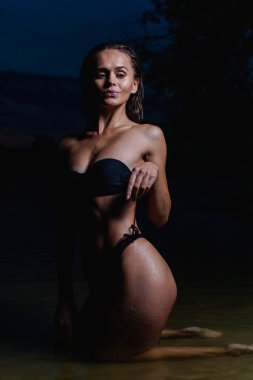 Suda güzel bir model. Gece için siyah bikini mayo, yüzme ve poz.