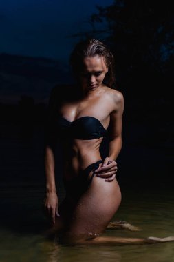 Suda güzel bir model. Gece için siyah bikini mayo, yüzme ve poz.
