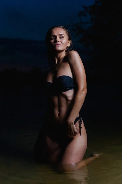 美丽的模型在水中 穿着黑色比基尼泳装过夜 游泳和摆姿势 — 图库照片