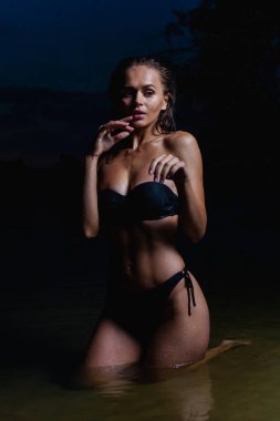 Suda güzel bir model. Gece için siyah bikini mayo, yüzme ve poz.