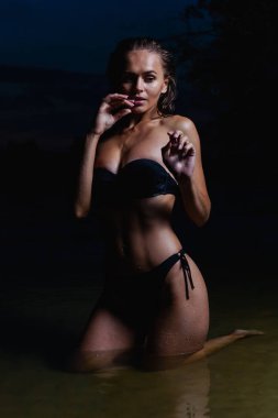 Suda güzel bir model. Gece için siyah bikini mayo, yüzme ve poz.