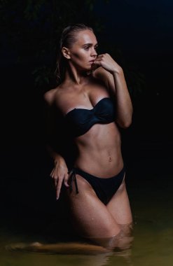 Suda güzel bir model. Gece için siyah bikini mayo, yüzme ve poz.