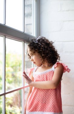 Pencerenin yanında evde küçük kız.