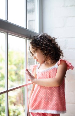 Pencerenin yanında evde küçük kız.
