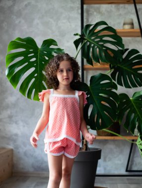 Monstera'lı küçük kız modeli. Monstera yaprakları ile küçük bir kız portresi.
