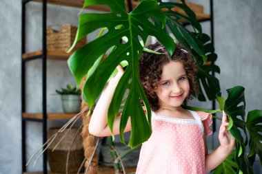 Monstera'lı küçük kız modeli. Monstera yaprakları ile küçük bir kız portresi.