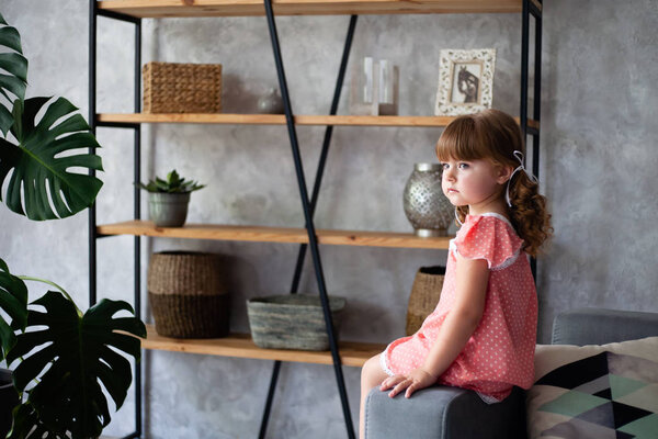 Little girl is sitting on the couch. In a nightgown.