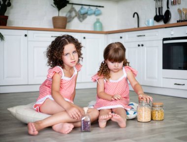 Küçük kızlar yerde otururken mutfakta oynanır.