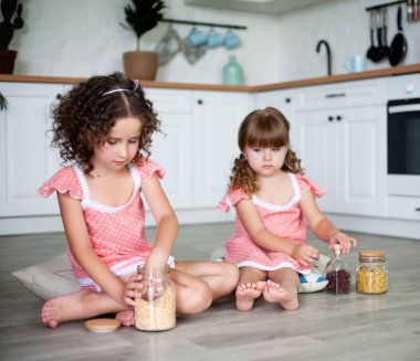 Küçük kızlar yerde otururken mutfakta oynanır.