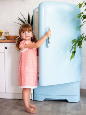 Küçük bir kız buzdolabının kapısını açar. Güzel mutfak.