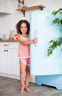 Küçük bir kız buzdolabının kapısını açar. Güzel mutfak.