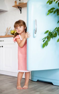 Küçük bir kız buzdolabının kapısını açar. Güzel mutfak.