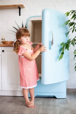 Küçük bir kız buzdolabının kapısını açar. Güzel mutfak.