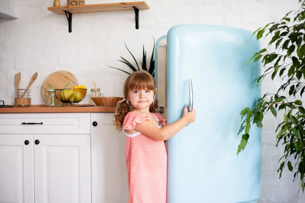 小さな女の子が冷蔵庫のドアを開けます 美しいキッチン — ストック写真