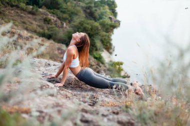 Kız yoga uyguluyor. Adanın dağ ve nehir kıyısında doğa ile çevrili.