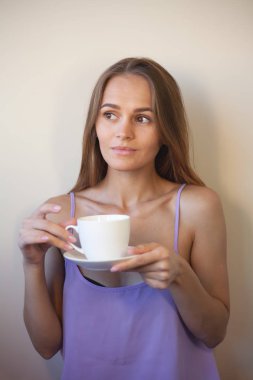 Genç bir kadın bir fincan kahvenin tadını çıkarıyor. Sabah çayı ile kadın portresi. Kopyalama alanı