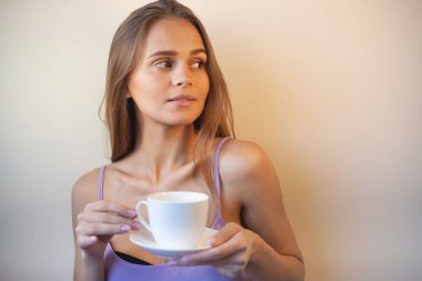 Genç bir kadın bir fincan kahvenin tadını çıkarıyor. Sabah çayı ile kadın portresi. Kopyalama alanı